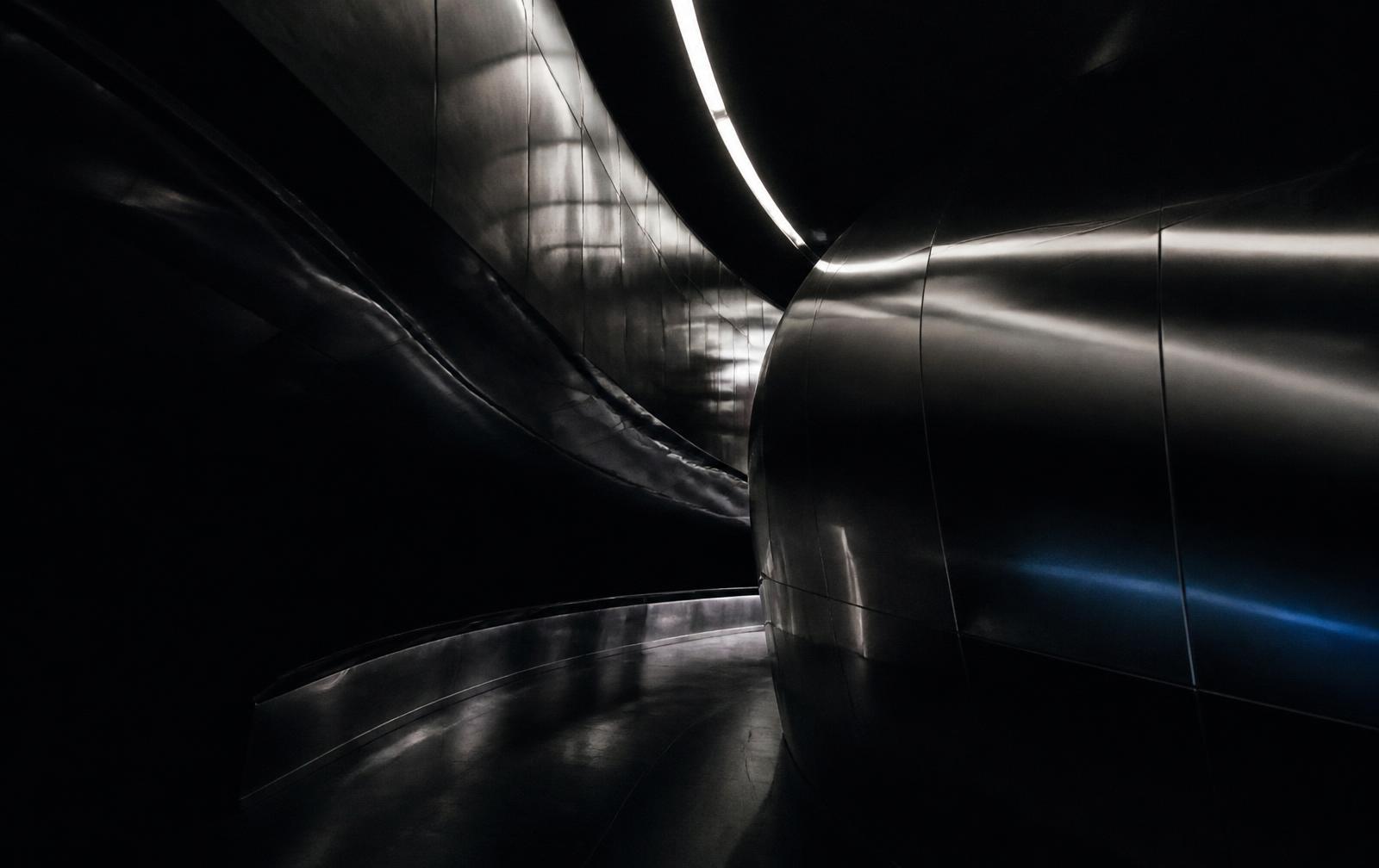 Curved black chrome architecture with a single light seam