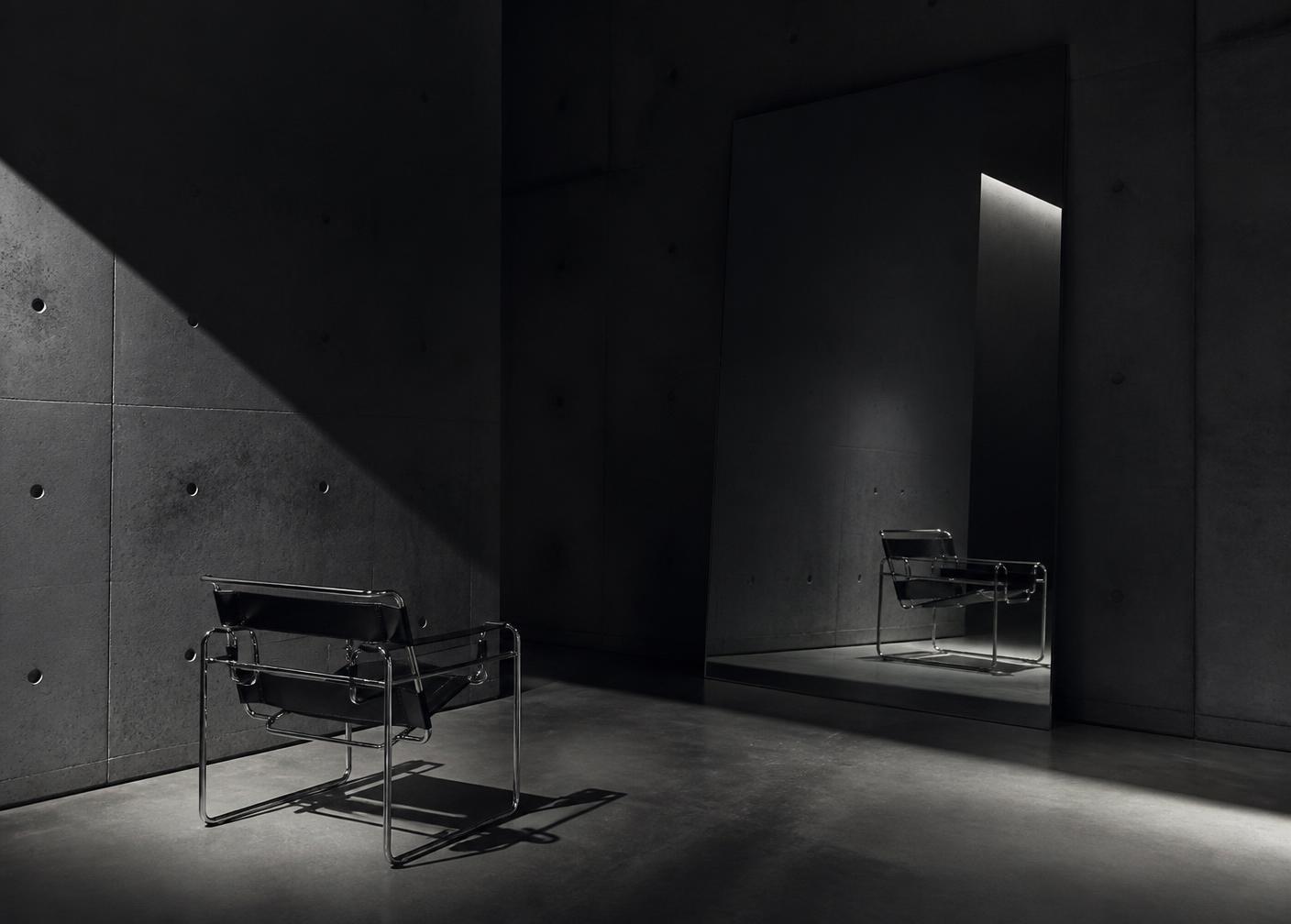 Chrome chair and tall mirror in a concrete void