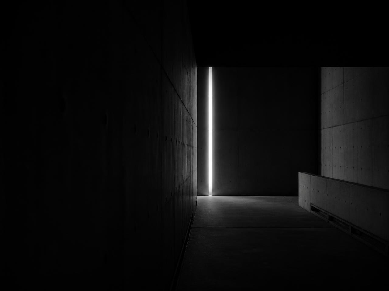 Brutalist concrete corridor cut by a single vertical light